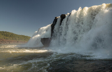 Sailing the river. The majestic Mocona waterfalls seen from the boat. The falling white water, rocks and river flowing across the jungle.