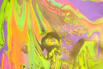 Mixture of acrylic bright paints with yellow gold glitter. Marble imitation background.