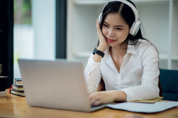 Online Education For Asian Young Women. Student Happy Arabic Girl In Headscarf And Headset Studying With Laptop At Home, Taking Notes While Watching Webinar