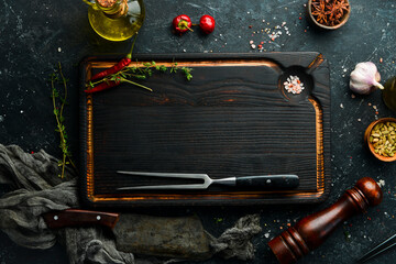 Dark kitchen wooden board with cutlery on a black stone background. Restaurant menu. Banner. Top view.