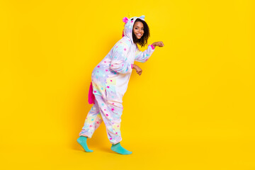 Full length body size view of attractive cheerful girl wearing pajama walking fooling isolated over bright yellow color background