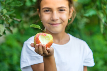 The child eats an apple in the garden. Selective focus.