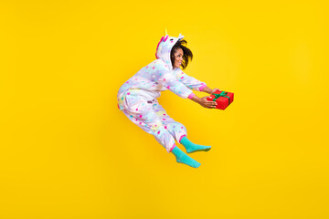 Fototapeta na wymiar Full length body size view of nice cheerful girl wearing kigurumi jumping giving giftbox isolated over bright yellow color background