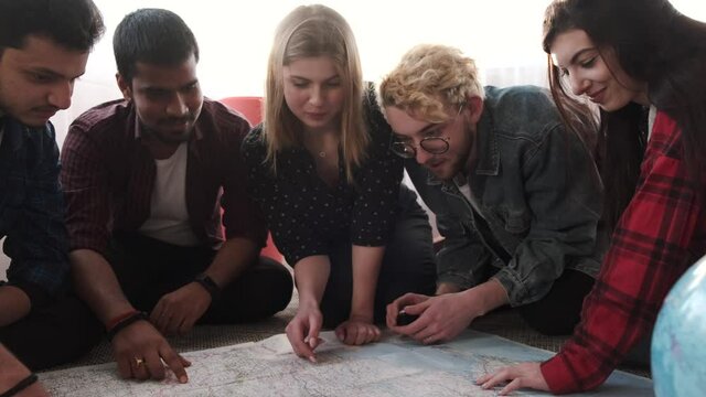 Group of diverse friends looking at map in the bright room