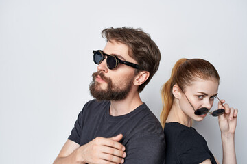fashionable man and woman in black t-shirt sunglasses posing light background