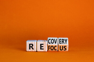 Refocus and recovery symbol. Businessman turned cubes and changed the word 'refocus' to 'recovery'. Beautiful orange table, orange background. Business refocus and recovery concept. Copy space.