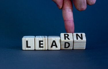 Learn and lead symbol. Businessman turns wooden cubes, changes the word 'learn' to 'lead'....