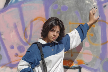 Schoolgirl girl posing against colorful graffiti wall