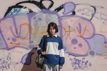 Schoolgirl girl posing against colorful graffiti wall