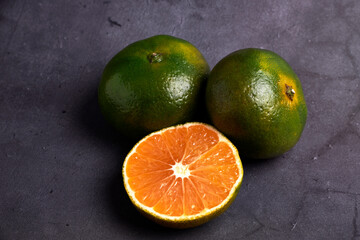 Fresh and juicy green mandarins on a dark background. Vegetarian food concept
