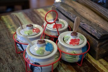 A set of glazed ceramic condiments on an old patterned wooden table in a noodle shop.