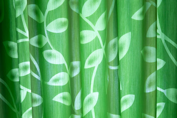 Green curtains with leaf motifs shine from outside the room with interesting shadows. For background.
