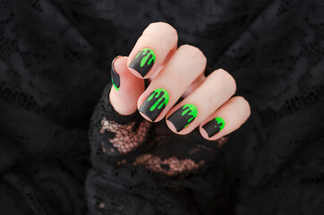 Close up womans hand with halloween spooky manicure on black background.