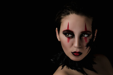 beautiful girl in makeup and feathers on a black background, halloween with a skull