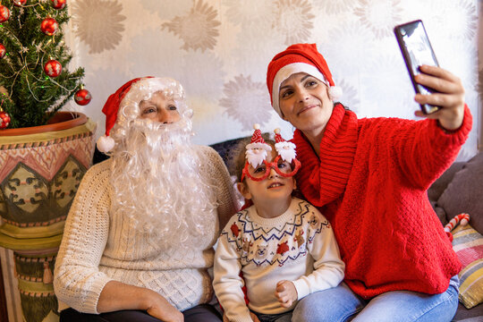 Family with red Christmas hats and funny glasses, taking a selfie