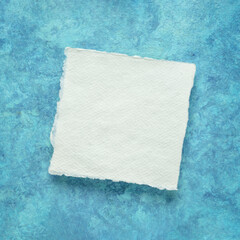 small square sheet of blank white Khadi paper against blue amate bark paper