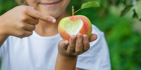 The child eats an apple in the garden. Selective focus.