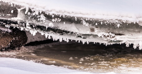Icicles and frost on a snow-covered frozen river