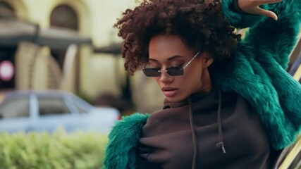 Curly-haired female dancer in trendy clothes performing rnb dance on street