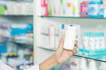 Hand woman pharmacist show drug bottle with her hand in drugstore. Pharmacist holds a packet of pills in her hand.