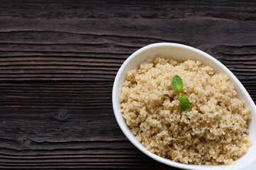 Bowl of boiled quinoa on wood background