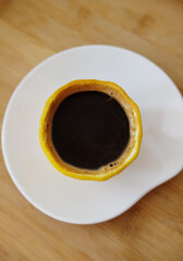 Creative serving of espresso romano coffee in a cup made of fresh lemon. Top view