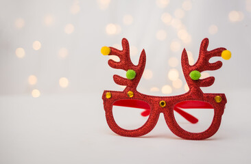 new Year's red glasses with deer antlers on a white background with bokeh