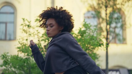 Professional female hip hop dancer with curly hair performing on city street