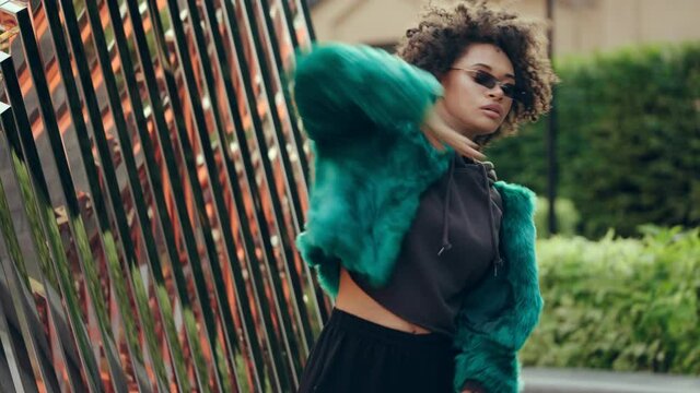 Beautiful biracial woman in fashionable wear dancing hip hop near urban space