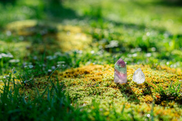 Beauterful purple fluorite and quartz crystals close up on natural forest green moss background in sun light. Spiritual esoteric practice, magic healing rock for reiki crystal ritual.