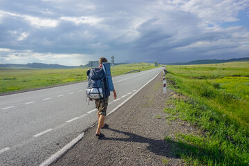 Traveler with a backpack walks along the road