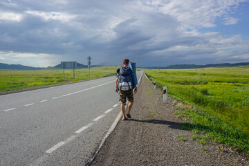 Obraz premium Traveler with a backpack walks along the road