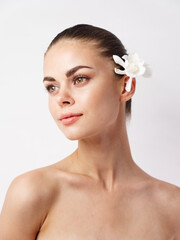 Obraz na płótnie Canvas beautiful woman with bare shoulders bright makeup white flower look to the side