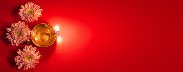 Happy Diwali. Diya oil lamp and flowers on red background. Traditional Hindu celebration. Religious holiday of light.