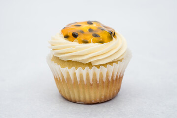 passion fruit cupcake decorated by a piping bag white cream on a marble background