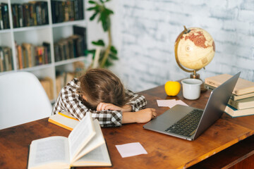 Side view of tired little child school girl sleeping at work desk lying on notebooks, exhausted child schoolgirl feeling lazy and unmotivated, doing boring school homework assignments.