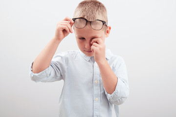 Small school guy rubs his eyes from long use of the computer