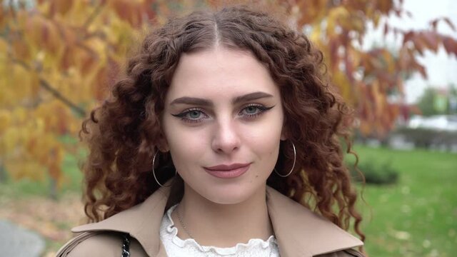 Portrait of a young beautiful curly woman on an autumn background outdoors