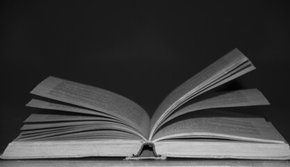 A gray old open book on a black background.