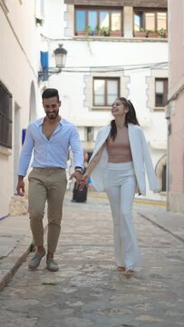 Stylish Hispanic couple speaking while walking in town