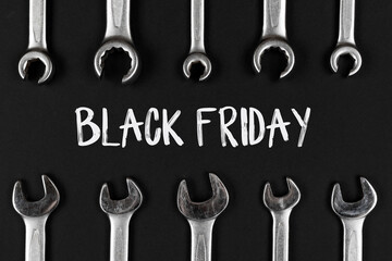 Black Friday sign on black, dark gray paper background with wrenches, spanners. Shopping concept