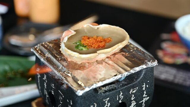 Kani miso with tobiko or crab paste in shell grilling on stove in japanese restaurant