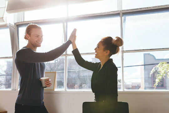 Guy and girl doing a high five to celebrate in an office