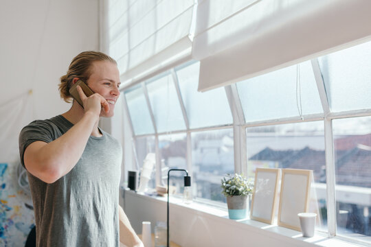 Young designer happily chatting on the phone in his studio