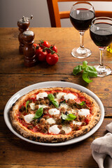 Pizza Napolitana or Naples style with mozzarella, basil and sausage