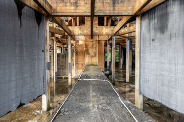 A view into an abandoned cooling tower with concrete pillars and walls in shades of grey and orange.
