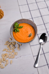 pumpkin soup with vegetables and spoon laying on white background