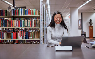 Young female Asian student working on her laptop at university library