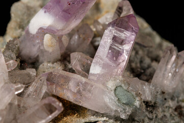 Macro mineral stone Amethyst crystals in rock on a black background