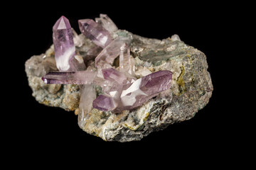 Macro mineral stone Amethyst crystals in rock on a black background